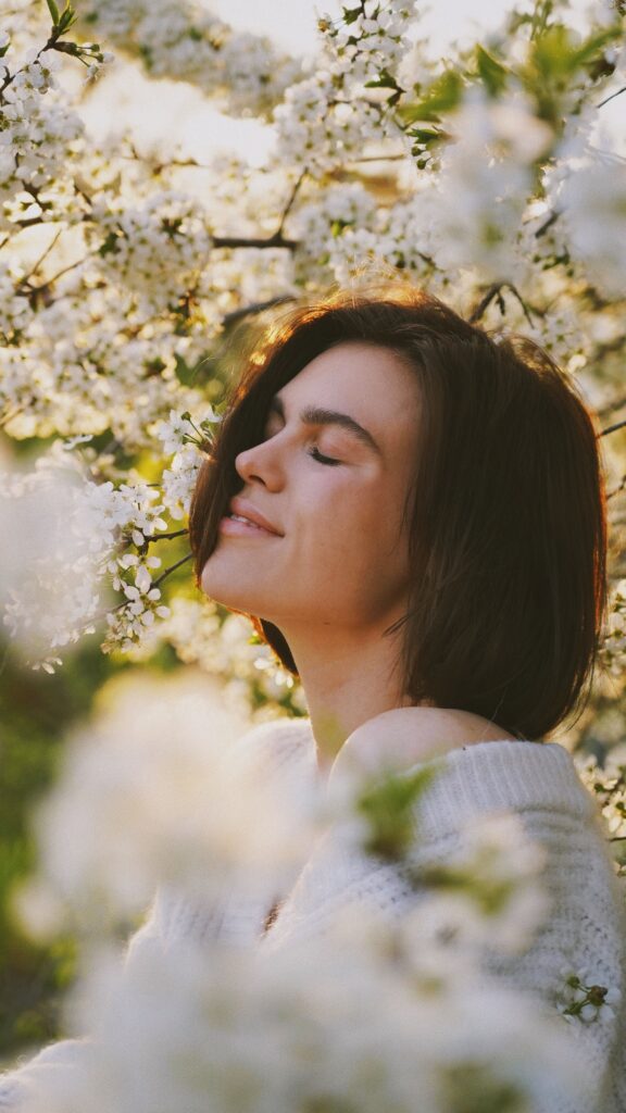 pexels-photo-11951727-11951727 A serene portrait of a woman among blooming spring flowers, eyes closed, feeling the freshness.