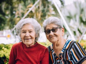 Two senior women enjoying a sunny day, smiling outdoors in Gigante, Colombia.